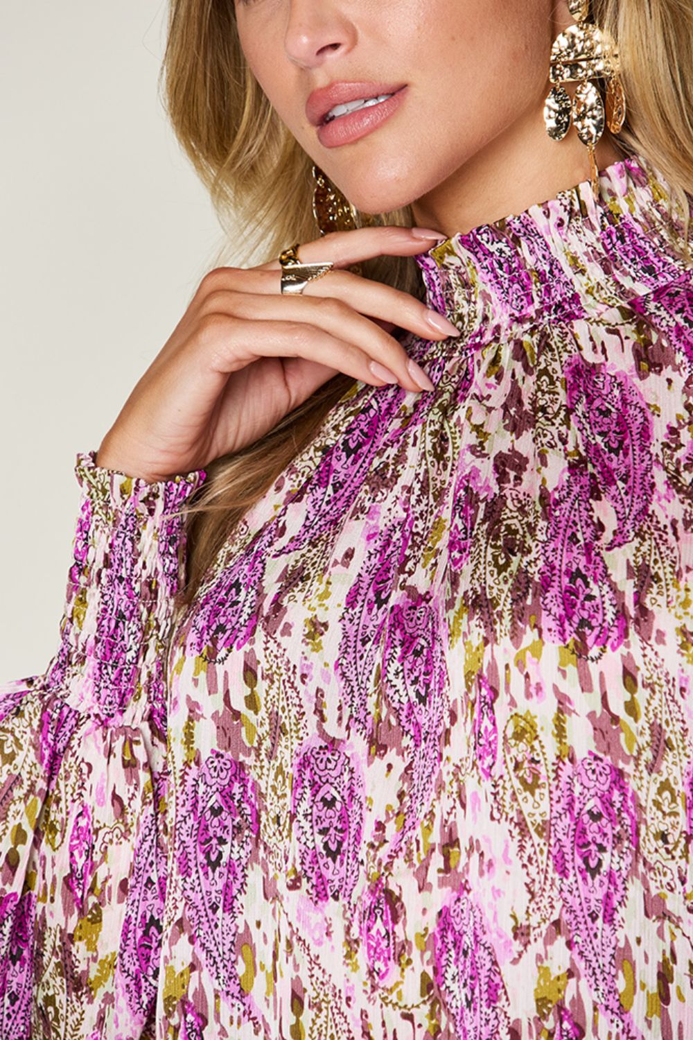 High neck abstract print blouse with smocked cuffs and collar in red-violet and white.