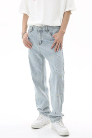 Light wash denim slouch trousers with colorful paint splatters and a relaxed fit.