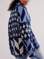 Geometric patchwork knit cardigan in blue with a shawl collar and button front, styled casually.