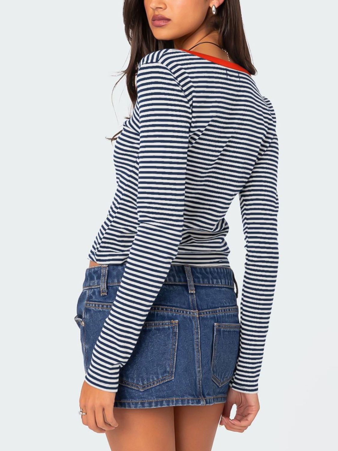 Striped long sleeve Henley shirt with contrast orange-red collar and button detail.