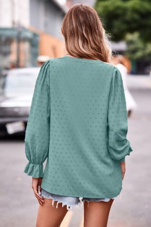 Turquoise textured dot v-neck blouse with ruffle cuffs and long sleeves.