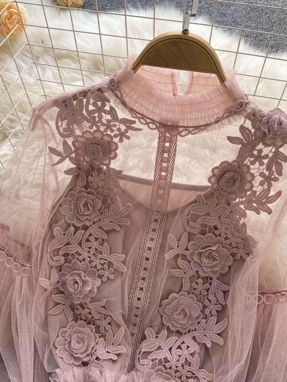 Light pink lace blouse with floral embroidery and ruffled mock neck.