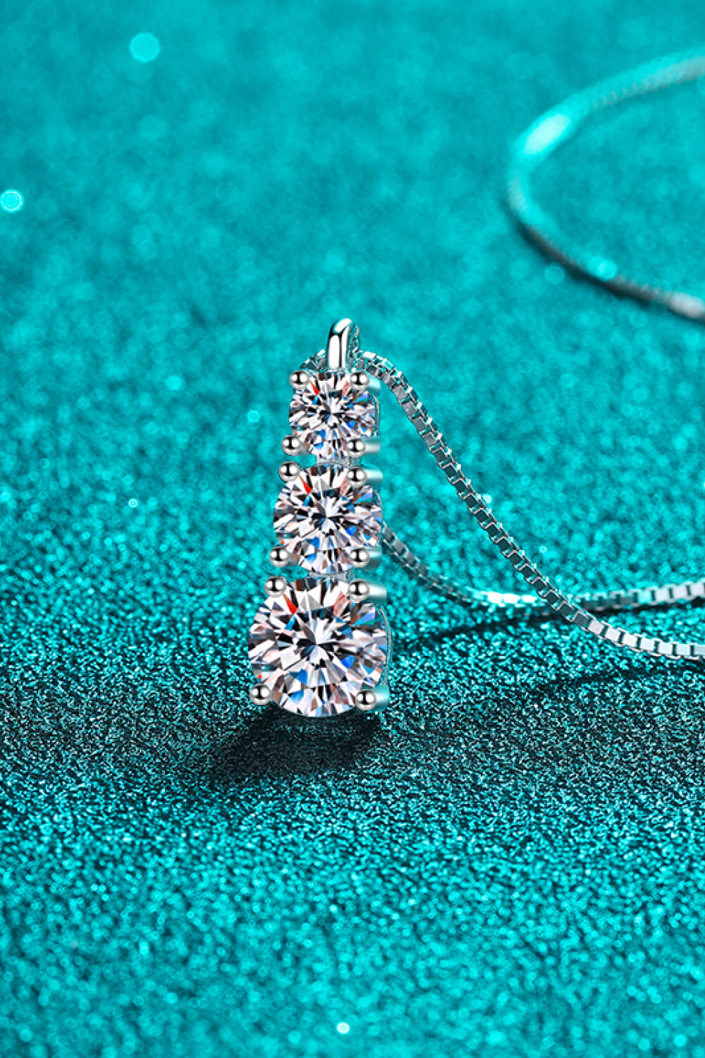 Silver moissanite pendant with three cascading stones on a box chain necklace.