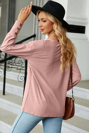 Blush pink blouse with diamond texture, V-neck, and button cuff sleeves.