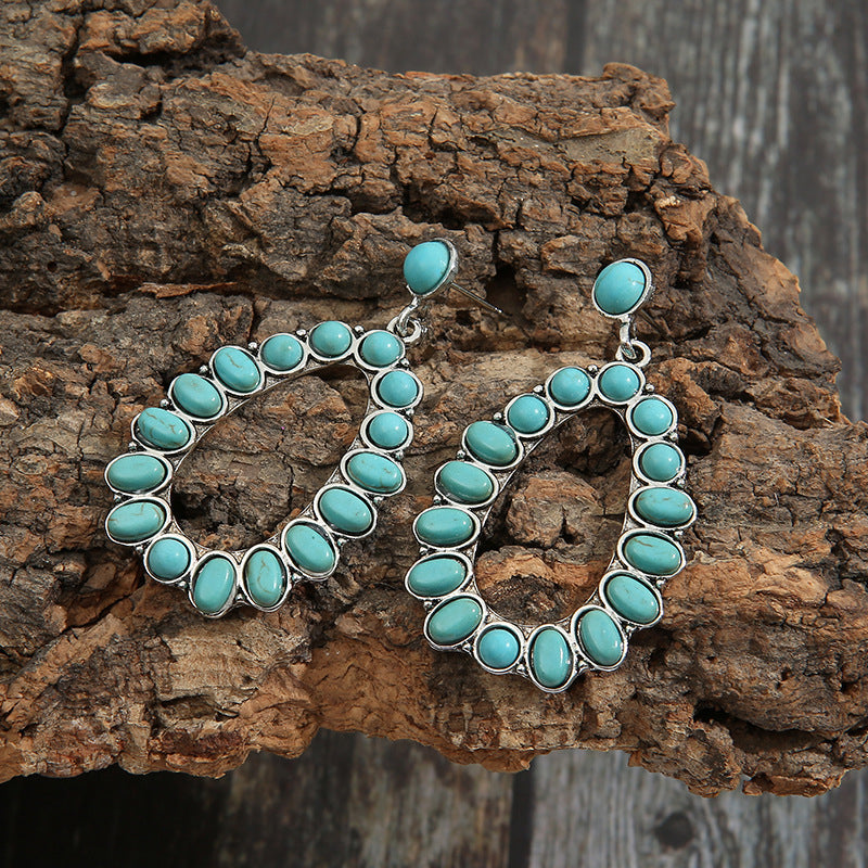 Teal teardrop statement earrings with artificial turquoise stones and silver alloy details.