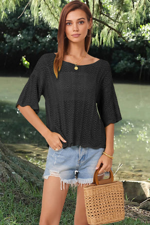 Black open-knit top with scalloped sleeves and boatneck, styled with denim shorts.