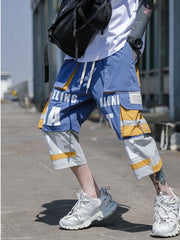 Color block utility cargo pants in light blue with yellow accents and graphic text detail.
