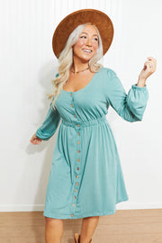 Button-down empire waist mini dress in green with long sleeves and a scoop neckline.