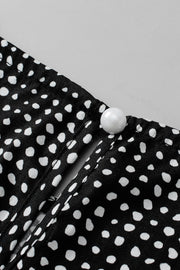 Black dotted blouse with a pearl button detail at the neckline.