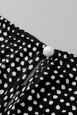 Black dotted blouse with a pearl button detail at the neckline.