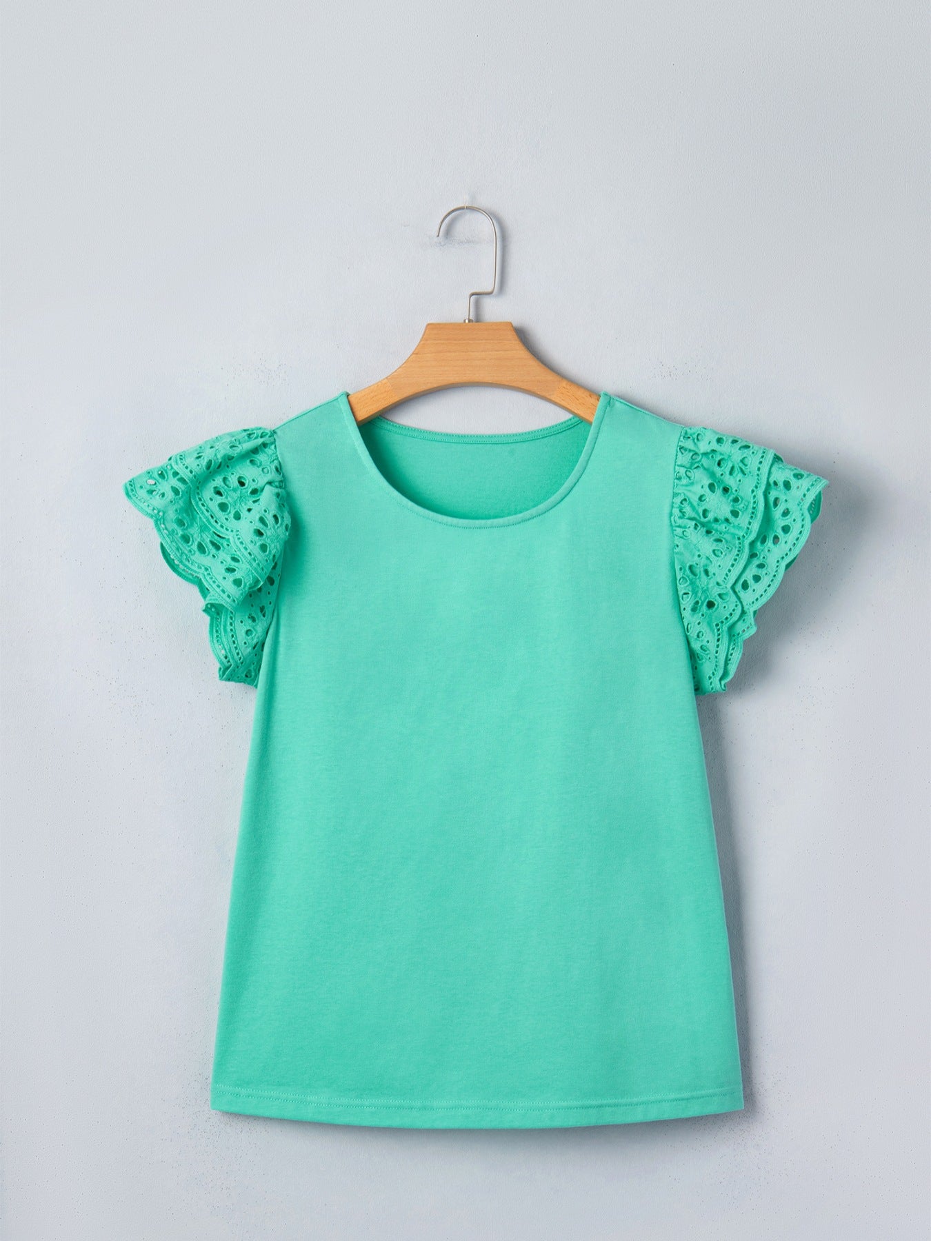 Eyelet lace ruffled cap sleeve top in green with a round neckline.