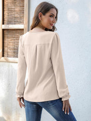 Beige textured pleat-front blouse with ruffle cuffs and long sleeves.