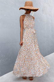Maxi dress with halter neckline, tiered skirt, and tie waist in a white and orange spot print.