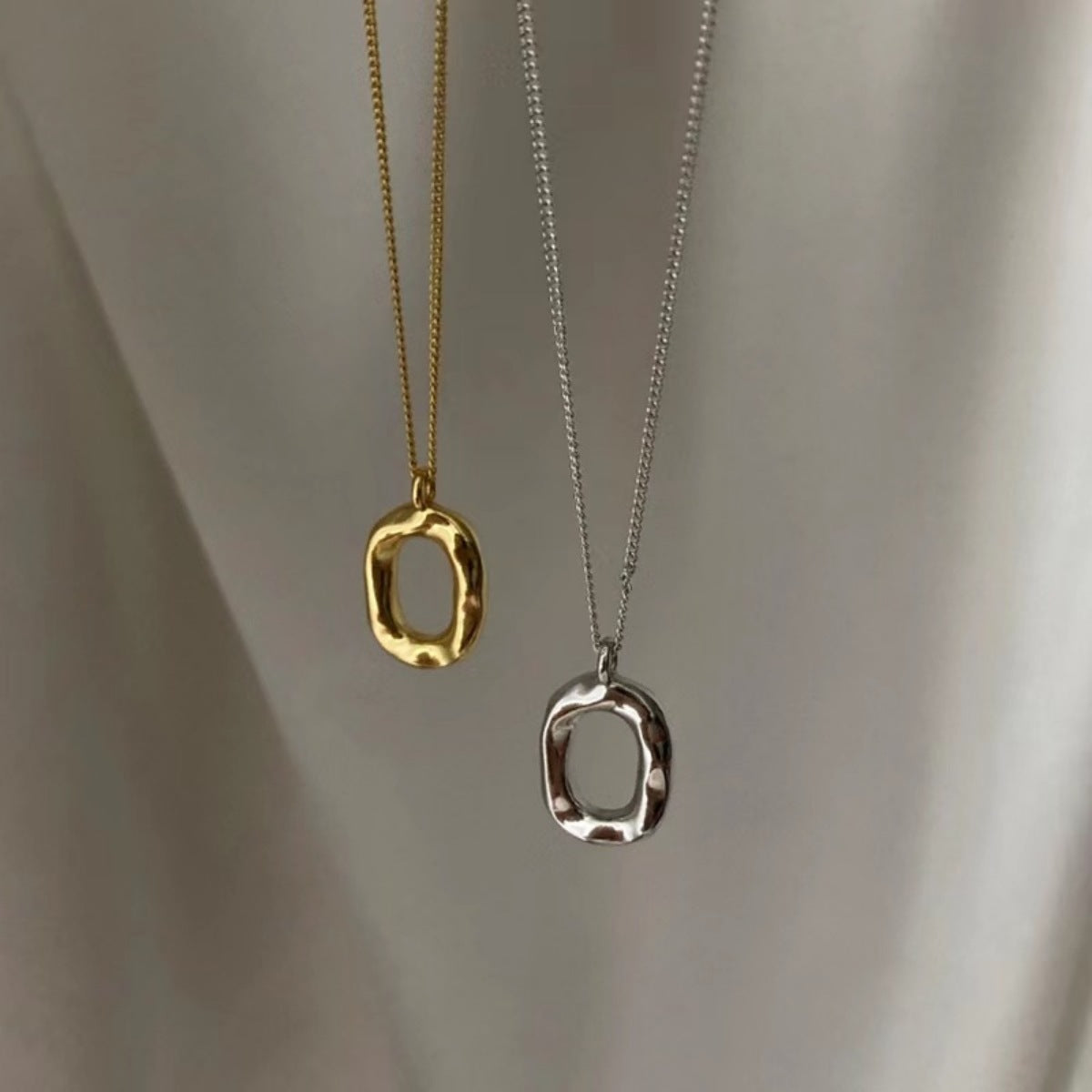 Geometric pendant necklaces in gold and silver with textured organic shapes.