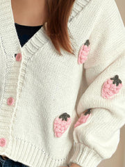White knit cardigan with pink strawberry appliqué and button front.