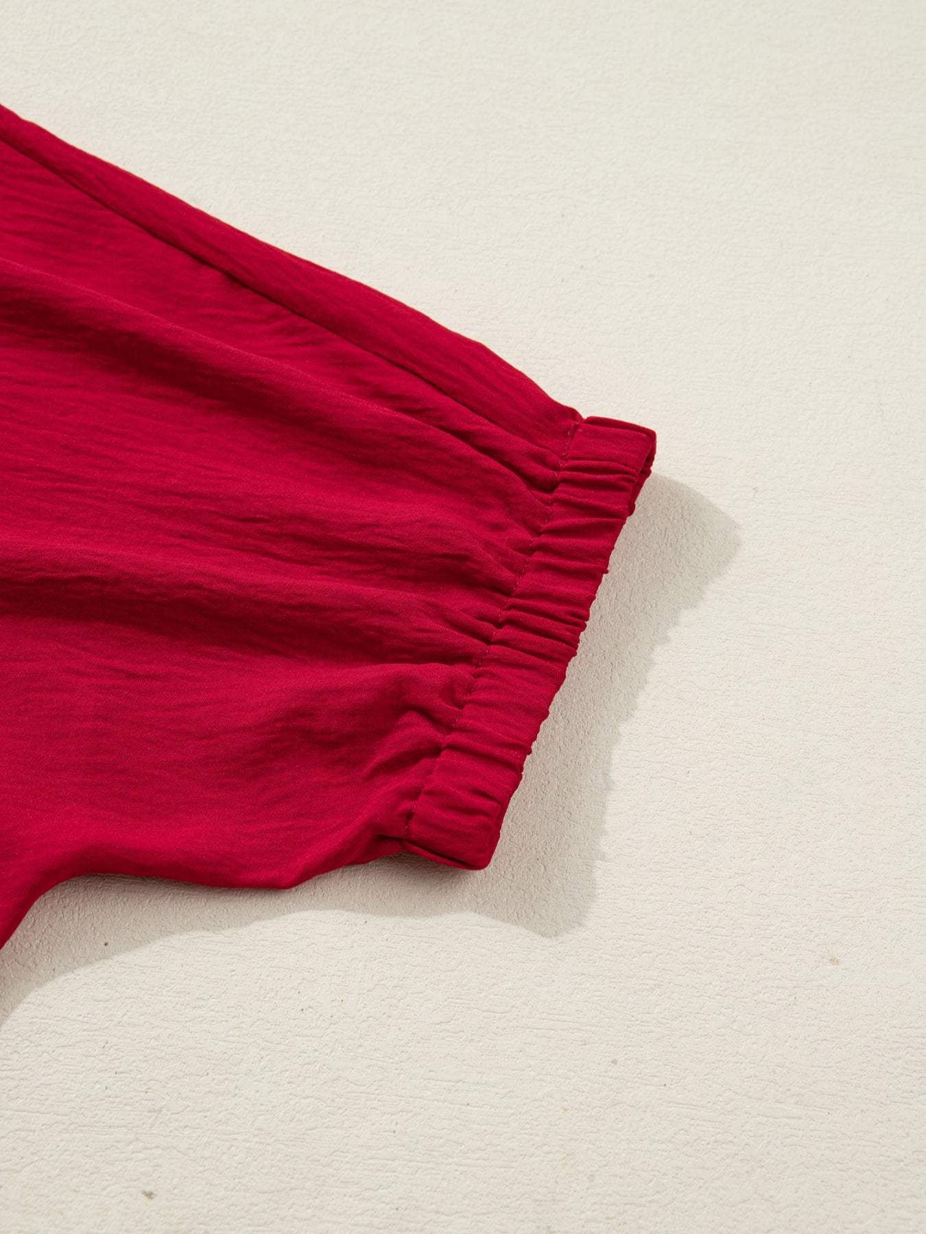 Deep red braided V-neck blouse with ruched half sleeves and crinkled texture.