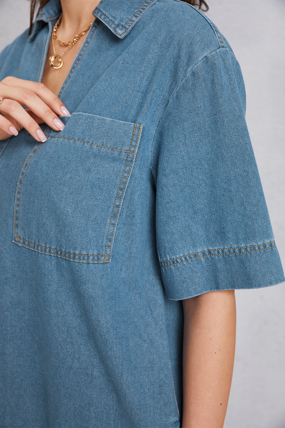 Denim mini dress in medium wash with a plunging collar, short sleeves, and a chest pocket.