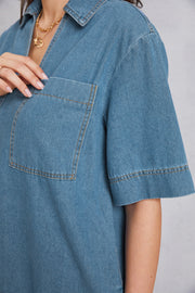 Denim mini dress in medium wash with a plunging collar, short sleeves, and a chest pocket.