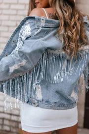 Denim trucker jacket in medium wash with distressed details and sequin fringe cascade.
