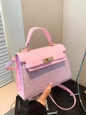 Pink glitter textured mini crossbody bag with gold hardware and top handle.