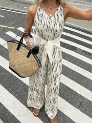 Chic tied waist wide-leg jumpsuit in abstract print with V-neck and sleeveless design.