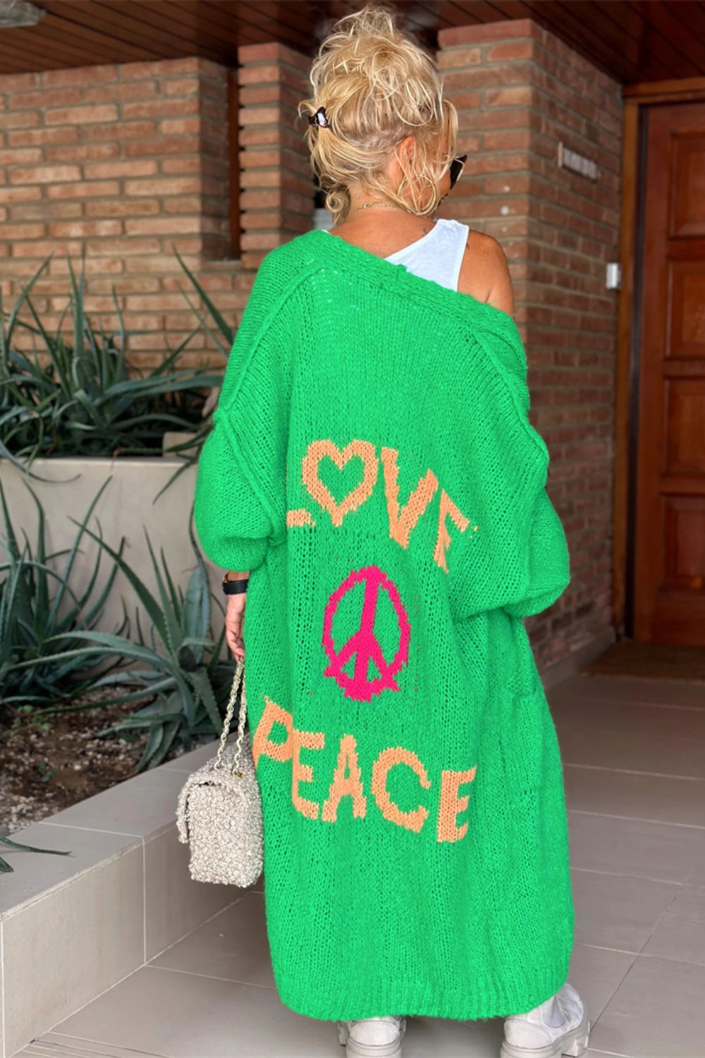 Green maxi knit cardigan with "LOVE PEACE" and peace sign graphic, long sleeves, open front