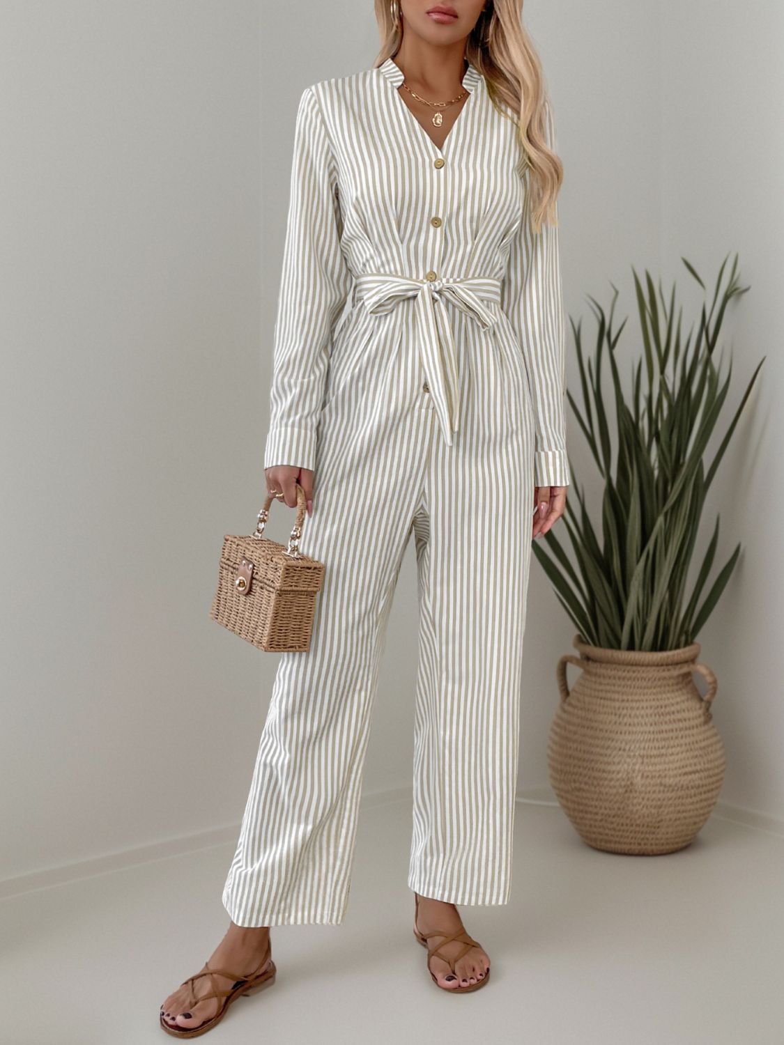 Beige vertical stripe button-down jumpsuit with tie waist and wide legs.