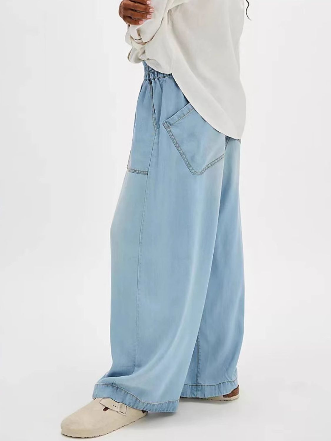 Light blue denim jeans with wide legs, elastic waist, and large back pockets.
