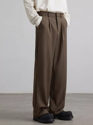 Brown pleated wide-leg trousers with a relaxed fit and side pockets.