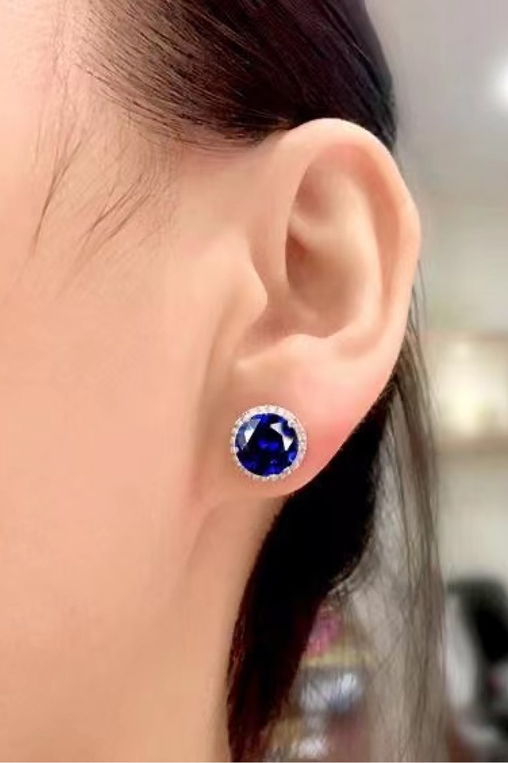 Blue sapphire halo stud earrings with diamond accents.