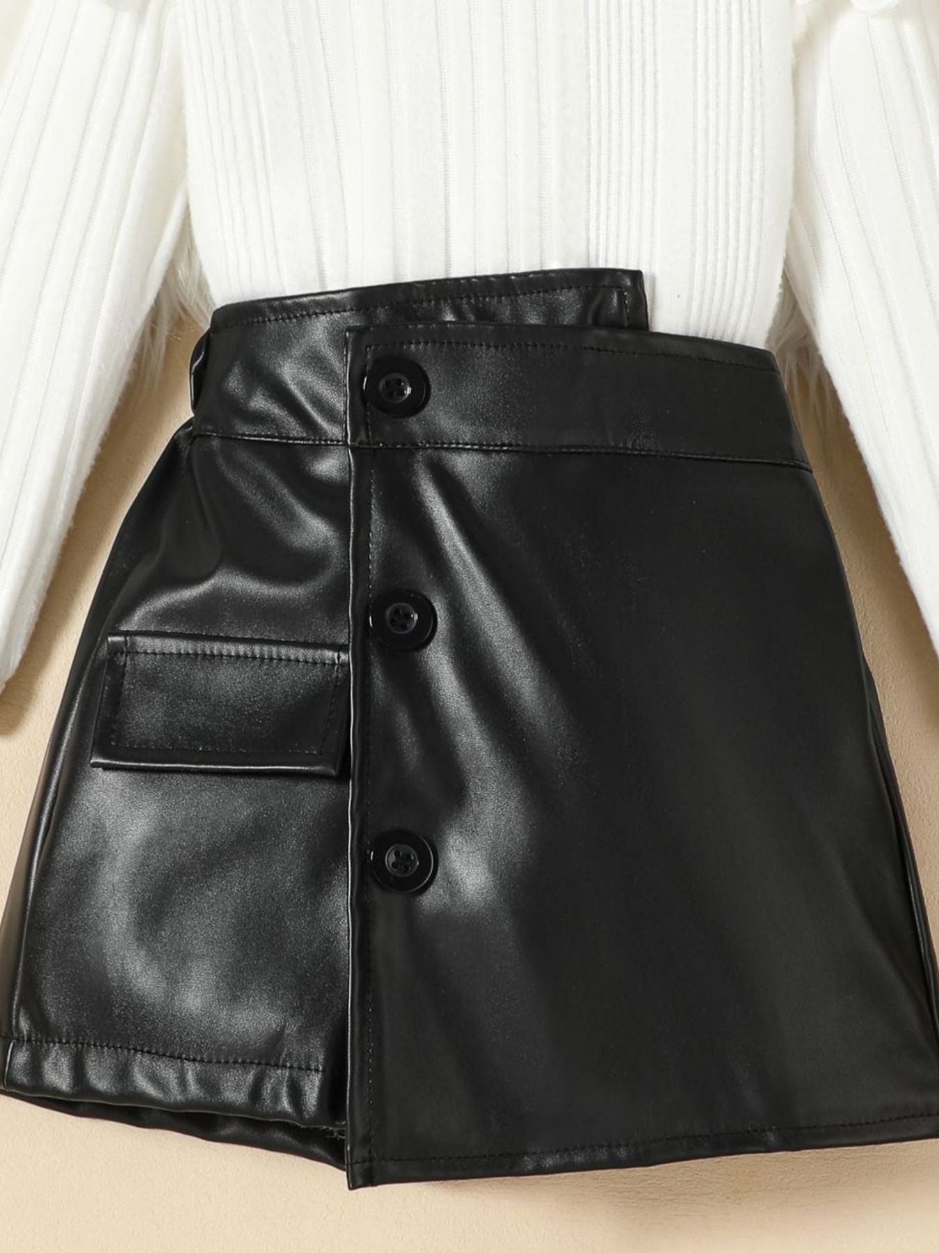 Black leather skirt with button front and pocket detail, paired with a ribbed knit top.