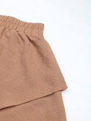 Camel tiered ruffle waistband shorts with textured fabric and elastic waist.