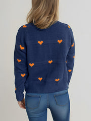 Dark blue knit sweater with orange heart pattern, crew neck, long sleeves, ribbed cuffs and hem.