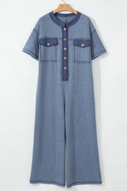 Dusty blue utility jumpsuit with denim trim, short sleeves, button front, and wide legs.