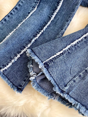 Denim flare pants with raw hem and white contrast stitching detail.