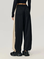 Black and beige panelled wide-leg track trousers with elastic waist and pockets.
