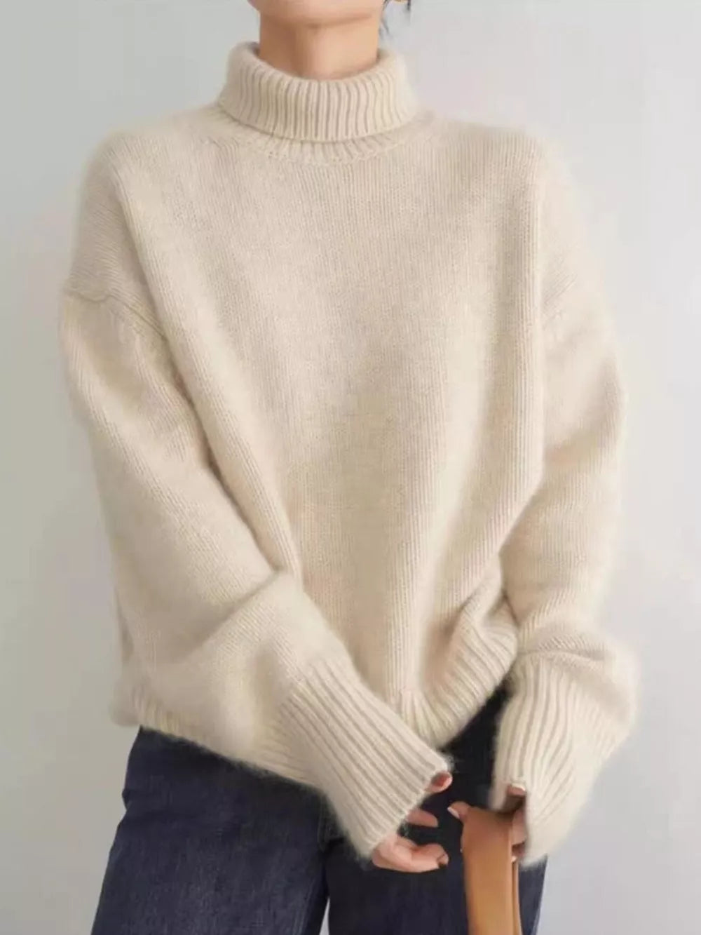 Cozy apricot turtleneck knit sweater with dropped shoulders and ribbed cuffs.