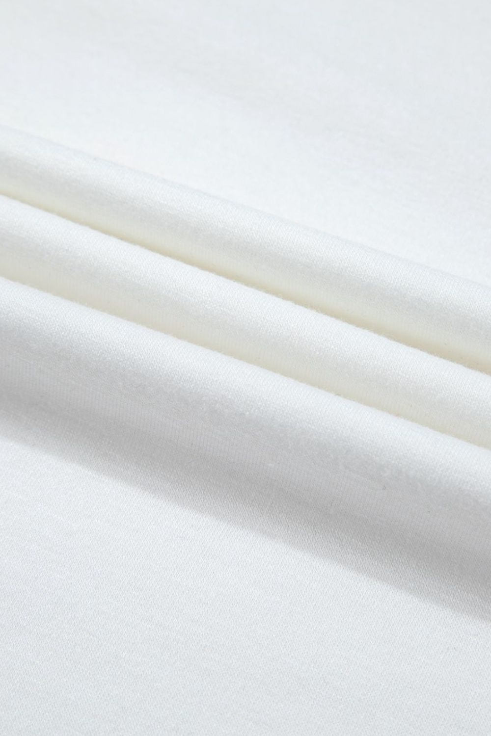 White loungewear fabric detail showing soft folds and texture.