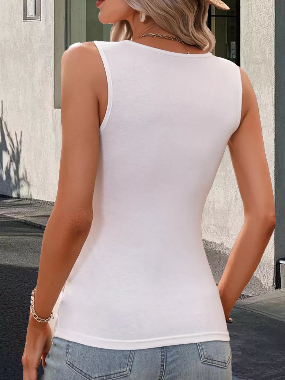 White sleeveless tank top with decorative buttons and a surplice neckline.