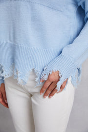 Light blue acrylic knit sweater with distressed hem and frayed edges.
