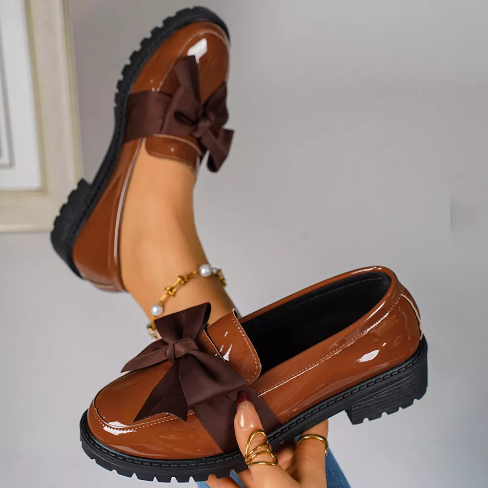 Chic brown patent loafers with bow detail and lug sole.