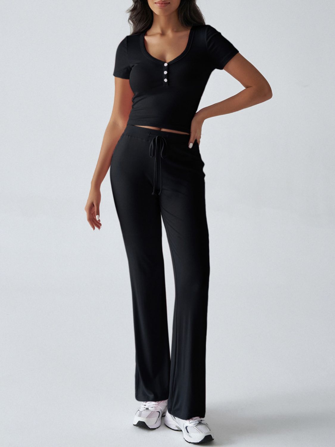 Black button-front crop top with short sleeves and black flared pants with drawstring waist.