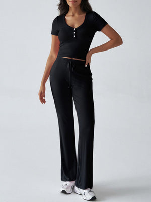 Black button-front crop top with short sleeves and black flared pants with drawstring waist.