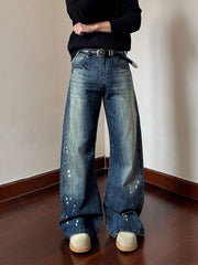 Men's vintage wash wide leg jeans in blue denim with paint splatters and a distressed look.