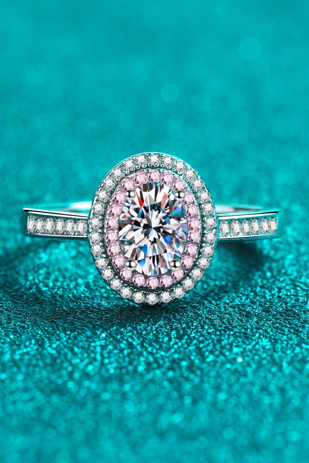Silver oval halo ring with pink stone accents and a central diamond.