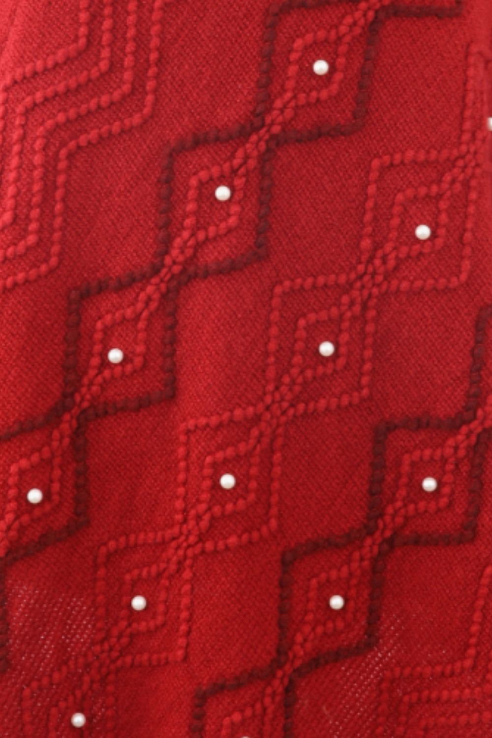Red knit poncho with geometric pattern and pearl embellishments