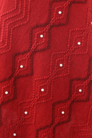 Red knit poncho with geometric pattern and pearl embellishments