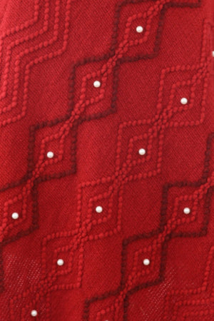 Red knit poncho with geometric pattern and pearl embellishments