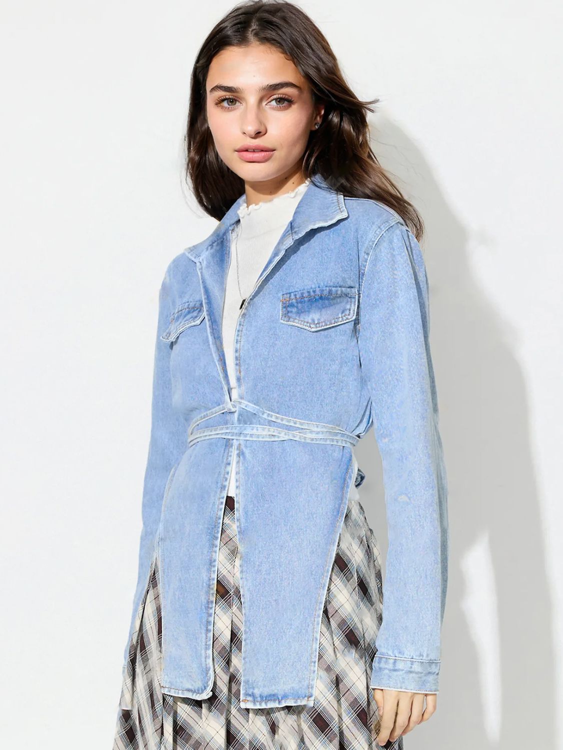 Medium wash denim wrap jacket with asymmetric hem and tie waist detail.