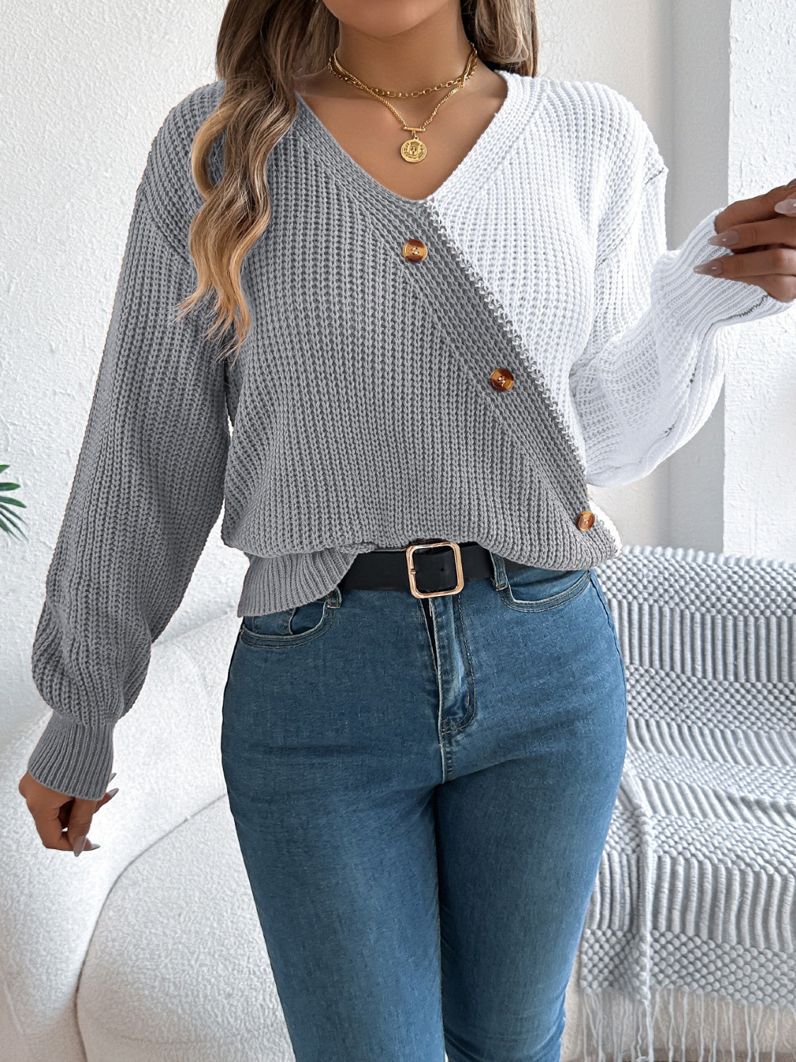 Asymmetrical colorblock knit sweater in gray and white with button details.